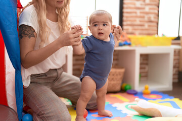 Teacher and preschool student standing with relaxed expression at kindergarten