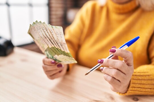 Middle Age Blonde Woman Ecommerce Business Worker Counting Hong Kong Dollars At Office