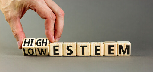 High or low esteem symbol. Concept words High esteem and Low esteem on wooden cubes. Businessman hand. Beautiful grey table grey background. Business high or low esteem concept. Copy space.