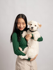 A portrait of a beautiful Indonesian Chinese girl in a green sweater holding a white Terrier dog, Isolated in a white background.