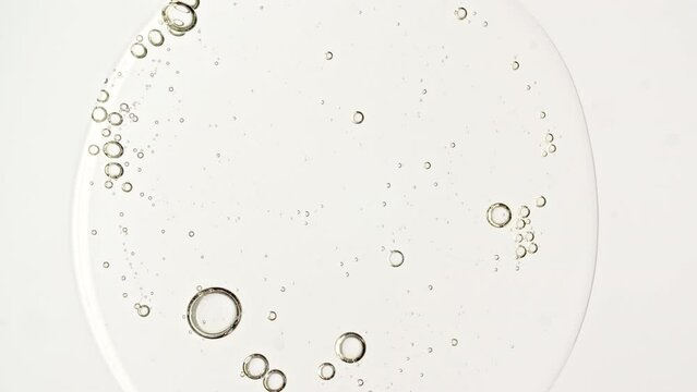 Transparent cosmetic gel fluid with molecule bubbles oil distribution on a white background. Macro Shot of Natural Organic Cosmetics, Medicine. Production Close-up. Slow Motion. High quality 4k