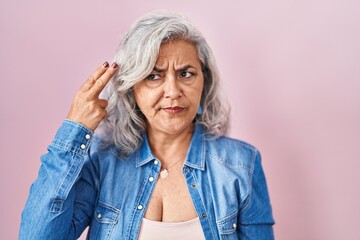Middle age woman with grey hair standing over pink background shooting and killing oneself pointing hand and fingers to head like gun, suicide gesture. - Powered by Adobe