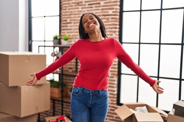 African american woman smiling confident standing with arms open at new home