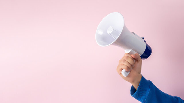 Man's hand with megaphone on pink background. Minimal advertising background.