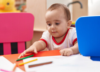 Adorable hispanic baby preschool student holding pencil color standing at kindergarten