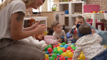 Teacher and preschool students playing with balls and cars sitting on floor at kindergarten