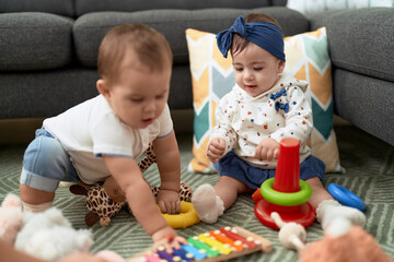 Two toddlers playing with toys sitting on floor at home