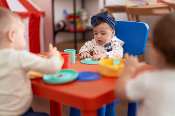 Group of toddlers learning to eat sitting on table at kindergarten