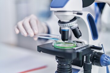 Young hispanic man scientist using microscope at laboratory