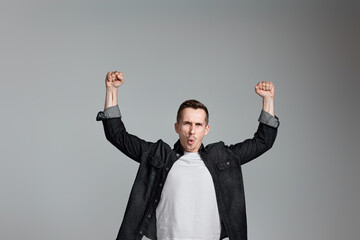 amazed man celebrating victory on gray background.