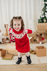 smiling child girl at home wearing christmas dress during christmas time