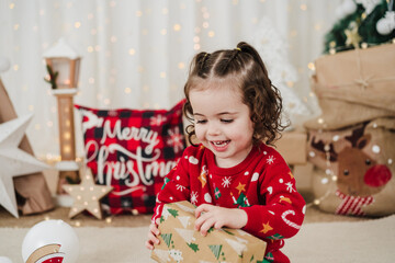 happy little girl at home holding presents during christmas time