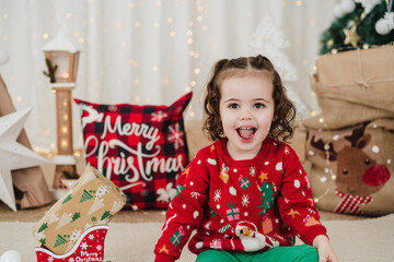 cute smiling little girl at home holding presents during christmas time