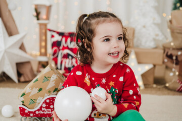 smiling little girl at home holding baubles during christmas time