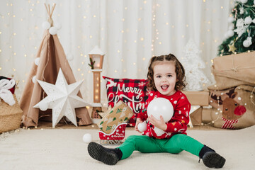 cute little girl at home holding baubles during christmas time