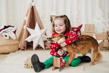 cute little girl at home embracing dog during christmas time