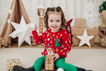 happy little girl at home holding baubles during christmas time