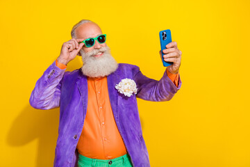 Portrait of funky grandfather toothy smile hold telephone make selfie isolated on yellow color...
