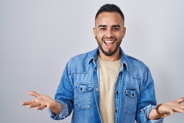 Young hispanic man standing over isolated background celebrating crazy and amazed for success with arms raised and open eyes screaming excited. winner concept