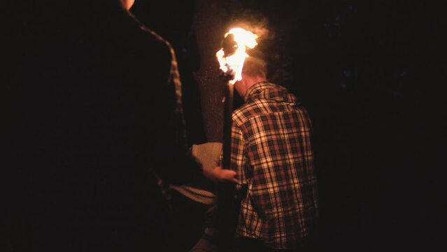 Friends tied man to tree, he is afraid and sad can't nothing done. Men wear retro clothes and use fire torch. Betrayal of friends in the ancient time in the dark forest
