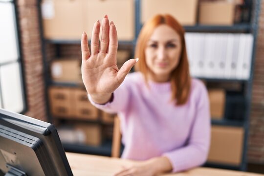 Young caucasian woman ecommerce business worker doing stop gesture with hand at office