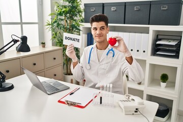 Young hispanic doctor man supporting organs donations smiling looking to the side and staring away thinking.