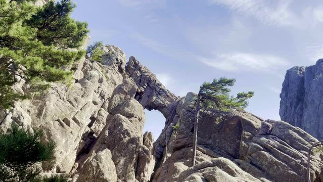 The Bomb Hole between the very rocky Corsican mountain range of the Aiguilles de Bavella in summer, very tall and wide massif of France, near Zonza in Conca forest, with some trees in bottom