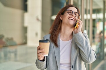 Young woman business worker talking on smartphone drinking coffee at street