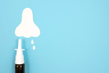 Nosal spray and nose silhouette with drops on a blue background. The concept of treatment of...