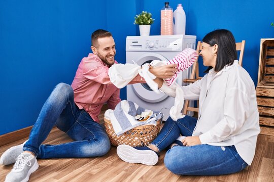 Man And Woman Couple Fighting With Clothes At Laundry Room