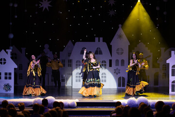 A collective of musicians, singers and dancers in gypsy costumes perform on stage.	