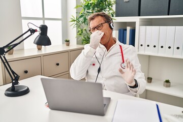 Senior doctor man working on online appointment smelling something stinky and disgusting,...