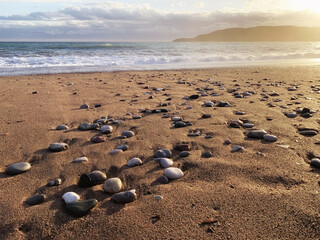 Fototapeta na wymiar Beauty sunset lights over the sea and coastline with sand and wet pebbles