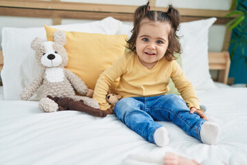 Adorable hispanic girl smiling confident sitting on bed at bedroom