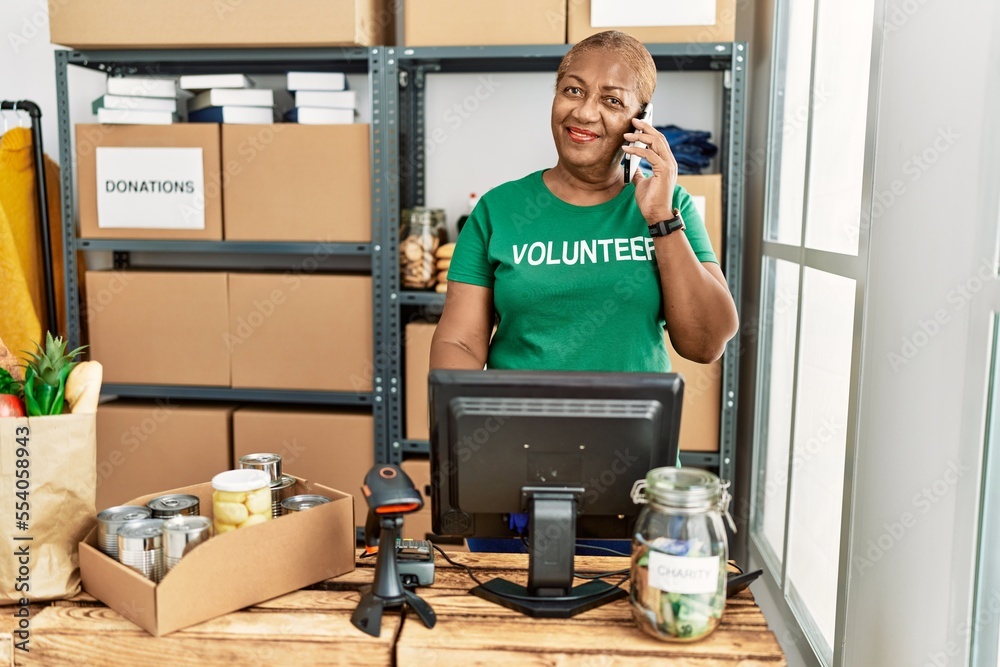 Canvas Prints Senior african american woman wearing volunteer uniform talking on the smartphone at charity center