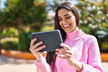 Fototapeta premium Young hispanic woman smiling confident watching video on touchpad at park