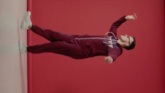A young man in sunglasses and a Christmas kigurumi dances on a red background.
