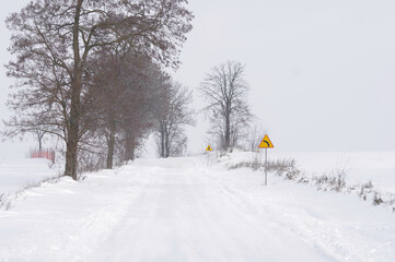 Znak ostrzegawczy, ostry zakręt, zima i ośnieżona droga. Trudne warunki do jazdy. - obrazy, fototapety, plakaty