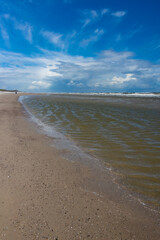 Sandy beach of Wangerooge island on the coast of Germany with shells on the North sea. National park, world natural heritage and perfect place for beachcombing and recreation. Windy day with blue sky.