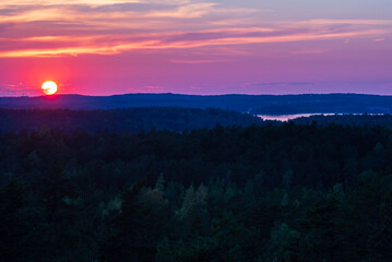 View of the sun setting over the forest and sea. Lemland, Åland Islands. Finland.