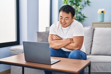 Young chinese man watching movie sitting on sofa at home