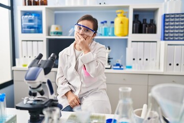 Hispanic girl with down syndrome working at scientist laboratory bored yawning tired covering mouth...