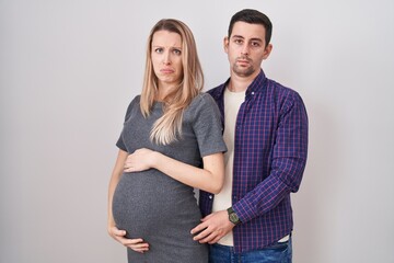 Young couple expecting a baby standing over white background depressed and worry for distress, crying angry and afraid. sad expression.