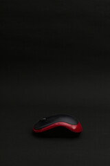 Black computer mouse with red stripe on black background