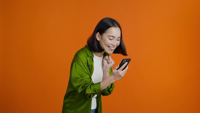Asian woman looks at mobile phone and exclaims joyfully