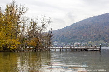 Fototapeta na wymiar autumn view of lake, trees and bench in Toscana Park, Gmunden, Austria