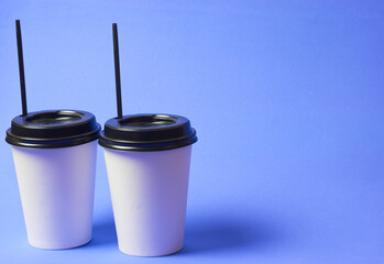 two glasses of takeaway coffee on a blue background