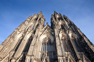 Cologne Cathedral seen from below with blue sky. Cologne Cathedral, or Kolner Dom, is the main landmark of Cologne and a catholic church in Germany....