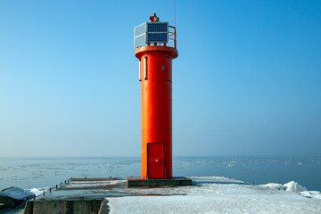Navigation red lighthouse with solar panels on Mangalsala pier in Baltic sea located at Riga sea...