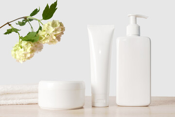 Obraz na płótnie Canvas White cosmetic cream and dispenser with white towel and hydrangea branch.